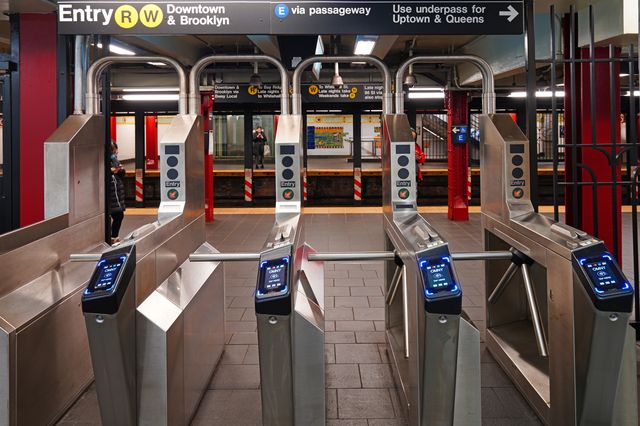 A view of four subway turnstiles, with OMNY readers, at an R & W subway station
